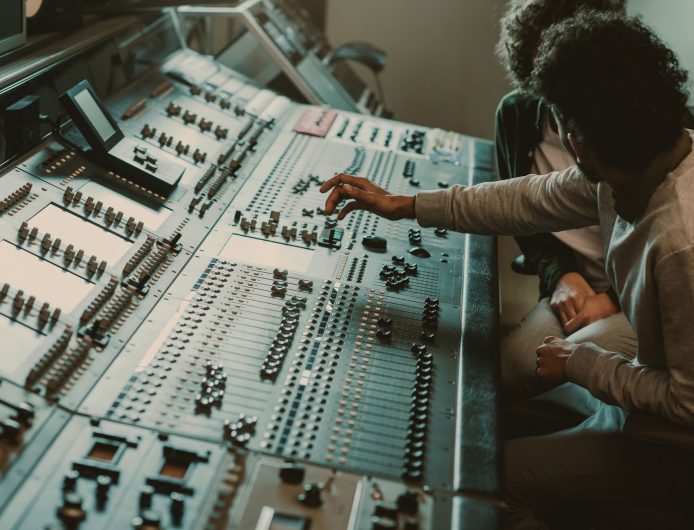 modern musicians working with graphic equalizer at recording studio